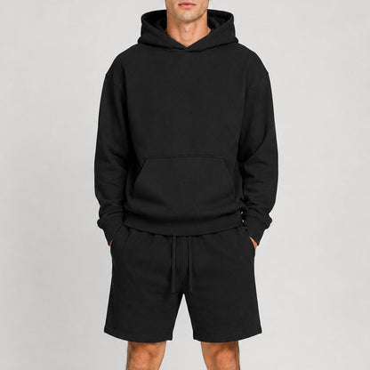 Person wearing a black hoodie and shorts set on a gray background