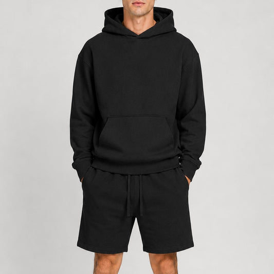 Person wearing a black hoodie and shorts set on a gray background